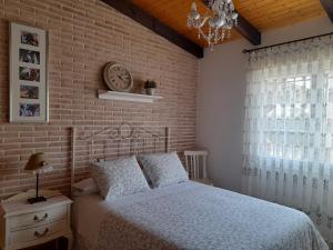 a bedroom with a bed and a brick wall at VIVENCIAS casa rural para 10 personas in Camuñas