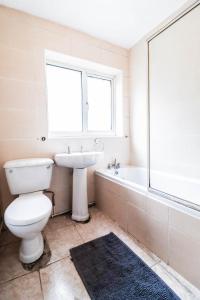 a bathroom with a toilet and a sink and a window at 5 bed house with driveway! in Luton