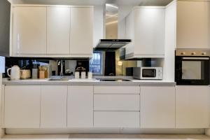 a white kitchen with white cabinets and appliances at Spacious Three Bedroom sleeps 7 secured free parking in Upholland