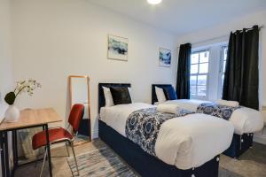 UphollandにあるSpacious Three Bedroom sleeps 7 secured free parkingのテーブルとデスクが備わる客室内のベッド2台