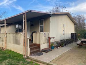 uma pequena casa branca com um alpendre e um pátio em Pomona em Chico
