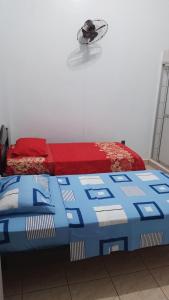 a bed with a red and blue comforter in a room at Alojamiento Oruro in Riberalta