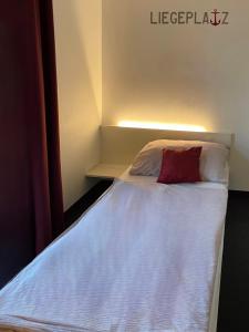 ein kleines Schlafzimmer mit einem Bett mit einem roten Kissen in der Unterkunft Hotel Caldor - 24h self-check in in Münchendorf