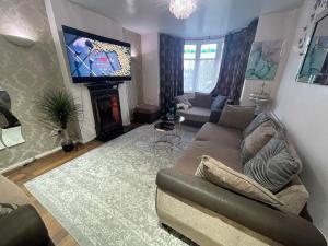 a living room with a couch and a television at Modern & Cozy 3 Bed House. in Wyken