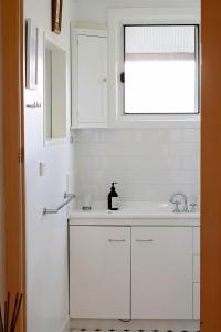 a white kitchen with a sink and a window at Borough Country House in Korumburra