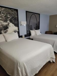 twee bedden in een hotelkamer met een foto aan de muur bij Super 8 by Wyndham Sullivan in Sullivan