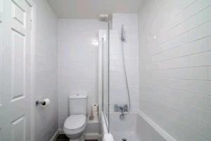 uma casa de banho branca com um WC e um chuveiro em Quiet 4 Bedroom House between Camden & Kings Cross em Londres