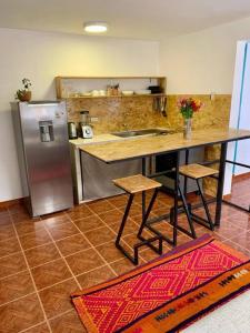 La cuisine est équipée d'une table et d'un réfrigérateur en acier inoxydable. dans l'établissement Departamento acogedor céntrico, à Cusco