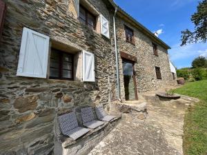 twee banken buiten een stenen gebouw bij La coruña Sas playa y golf in Paderne