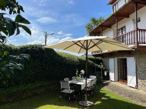 a table with an umbrella in front of a house at La coruña Sas playa y golf in Paderne