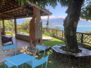 a table and chairs under a tree with a view at Casas No Centro Histórico (vila) in Ilhabela
