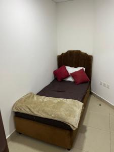 a small bed with two red pillows on it at F22R4 Small room attach bath at beach in Ajman 