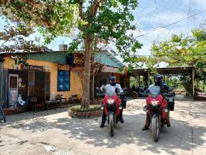two people on motorcycles parked in front of a building at LA'S FARMSTAY in Tây Ninh