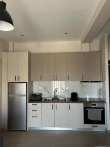 uma cozinha com armários brancos e um frigorífico de aço inoxidável em La Viella em Gastoúni