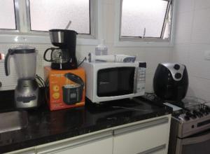 a kitchen counter with a microwave and a blender at Apt Guarujá Enseada lado praia FAN 1 dorm Tv Netflix Wi-Fi Ar até 5 pessoas in Guarujá