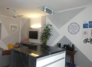 a kitchen with a counter top with a tv on a wall at Apt Guarujá Enseada lado praia FAN 1 dorm Tv Netflix Wi-Fi Ar até 5 pessoas in Guarujá