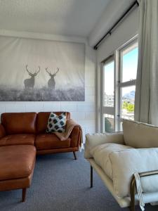 sala de estar con sofá y 2 ciervos en la pared en Wee Dram en Queenstown