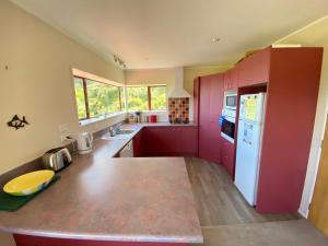 a kitchen with red cabinets and a white refrigerator at Pohara's Kauri Lodge in Pohara