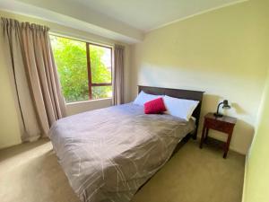 1 dormitorio con 1 cama con 2 almohadas y ventana en Pohara's Kauri Lodge, en Pohara