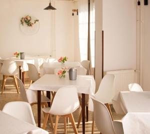 uma sala de jantar com mesas brancas e cadeiras brancas em Castle Residence Balaton em Balatonföldvár