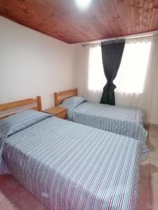 twee bedden in een kamer met een raam bij Alojamiento en el centro de Paipa in Paipa