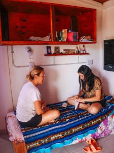 dos personas sentadas en una cama en una habitación en El Colibrí - Quebrada de la Luna. en 