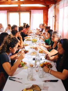 un grupo de personas sentadas en una mesa larga comiendo comida en El Colibrí - Quebrada de la Luna. en 