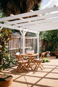 a wooden table and chairs under a white pergola at Soul Sister Cottage in Invermay