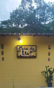 a sign on the side of a yellow building at Casa da Lu in Macaé