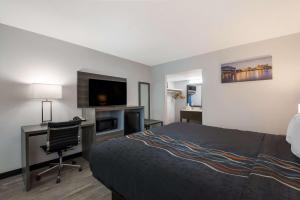 een hotelkamer met een bed, een bureau en een televisie bij Rodeway Inn in Cleveland