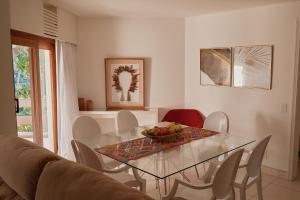 a dining room with a glass table and chairs at Flat Amplo e Confortável à Beira Mar em Jatiúca! in Maceió