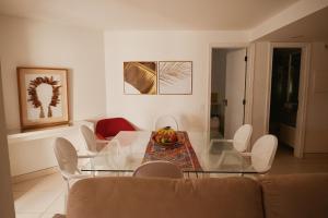 uma sala de estar com uma mesa de vidro e cadeiras brancas em Flat Amplo e Confortável à Beira Mar em Jatiúca! em Maceió