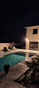 uma piscina numa casa à noite em magnifique villa avec piscine et spa em Merville