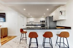 a kitchen with white cabinets and two bar stools at In-between the Coast and the City in Everett
