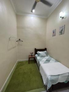 HomestayMuslim Safiyya في سونغاي بيتاني: غرفة نوم بسرير وسجادة خضراء