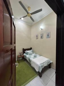 een slaapkamer met een bed en een plafondventilator bij HomestayMuslim Safiyya in Sungai Petani