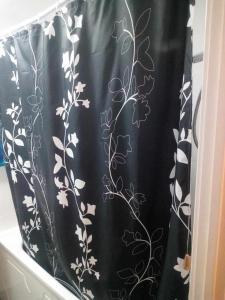 a black shower curtain with white flowers on it at Cosy furnished double room in a great quiet location walking distance to seaside and town in Kent