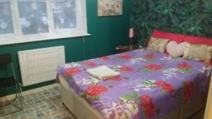Cosy furnished double room in a great quiet location walking distance to seaside and town في Kent: سرير مع لحاف أرجواني عليه زهور