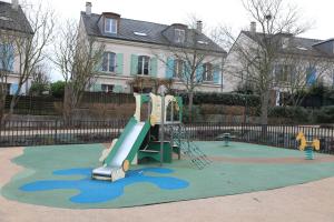 Un parque infantil con un tobogán en un patio en La Suite Est-Versaillais, en Saint-Cyr-lʼÉcole