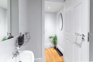 uma casa de banho branca com um lavatório e um espelho em 3BDR Extremely rare luxury loft maisonette em Londres