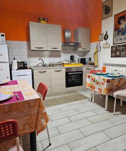 una cocina con paredes de color naranja, electrodomésticos blancos y mesas. en B&B Villa Emilia Milano, en Milán