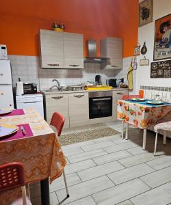 kuchnia z pomarańczowymi ścianami oraz białymi urządzeniami i stołami w obiekcie B&B Villa Emilia Milano w Mediolanie