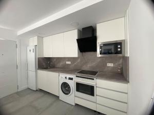 una cucina con armadi bianchi e una lavatrice/asciugatrice di Casa Blanca a Guaro