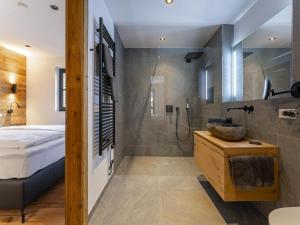 a bathroom with a shower and a bed and a sink at Haus am Hang in Saalbach-Hinterglemm