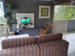 a living room with a couch and a television at Casa Azul da Cor do Mar in Paraty