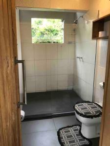 ein Bad mit Dusche, WC und Fenster in der Unterkunft Casa Azul da Cor do Mar in Paraty
