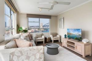ein Wohnzimmer mit einem Sofa und einem TV in der Unterkunft Harbourside #53 in Sydney