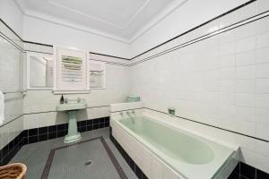 a white bathroom with a tub and a sink at Sunrise House in Hazelbrook