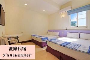 a bedroom with two beds and a desk and a television at FUNSUMMER in Green Island