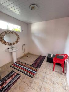 a bathroom with a sink and a red chair at Tikehau HereArii Airbnb in Tikehau